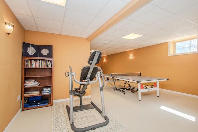 exercise area featuring baseboards, a drop ceiling, and carpet floors