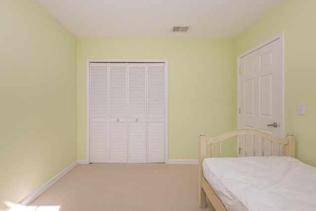 bedroom with visible vents, baseboards, light colored carpet, and a closet