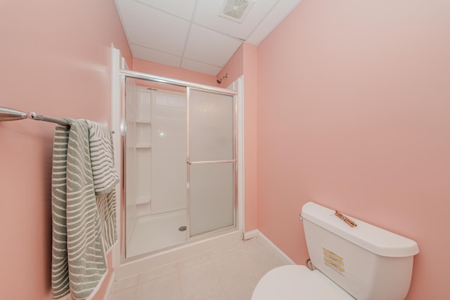 bathroom with tile patterned flooring, toilet, a paneled ceiling, and a stall shower