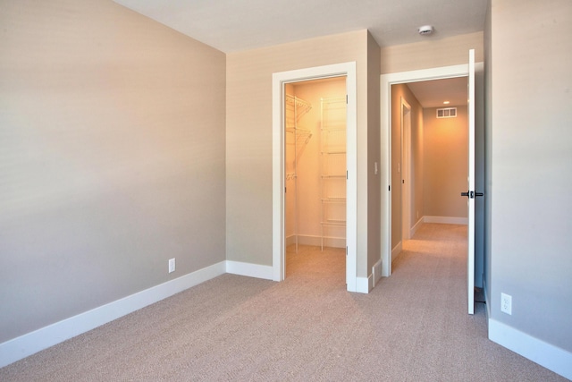 unfurnished bedroom with a spacious closet, carpet flooring, baseboards, and visible vents