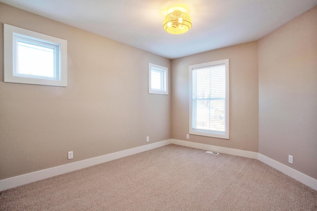 spare room with baseboards, visible vents, and light carpet