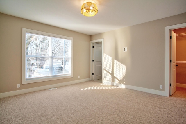 unfurnished room with baseboards, visible vents, and light carpet