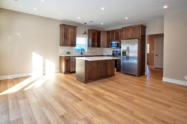 kitchen with a sink, stainless steel appliances, light countertops, tasteful backsplash, and a center island