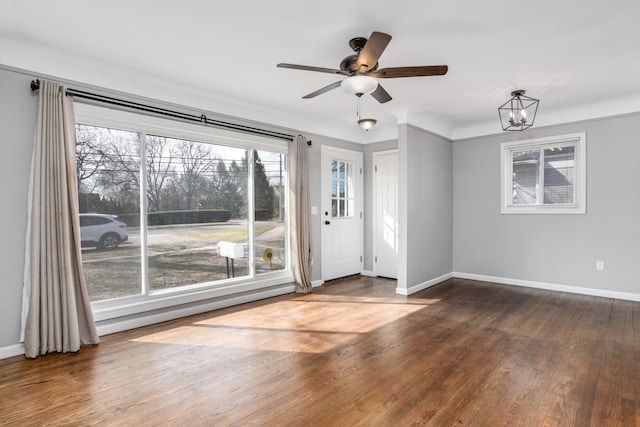 unfurnished room featuring ceiling fan with notable chandelier, baseboards, and hardwood / wood-style flooring