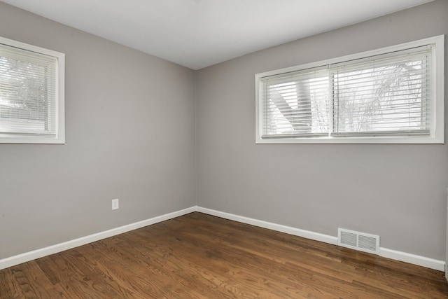 unfurnished room with visible vents, baseboards, and wood finished floors