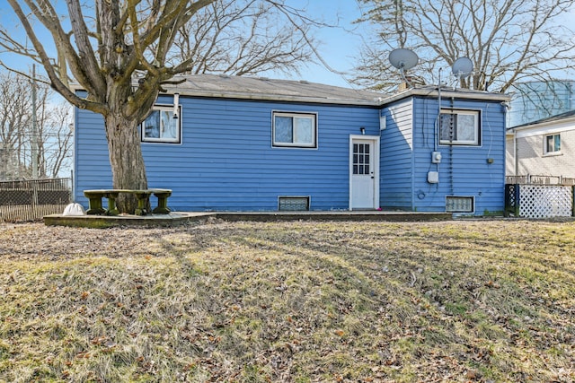 rear view of property featuring fence and a lawn