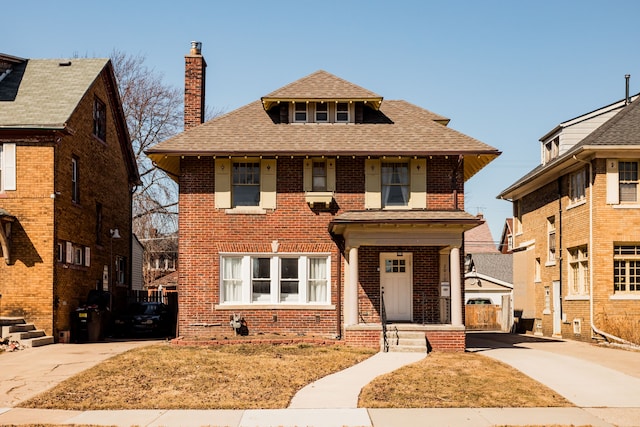 american foursquare style home with a chimney, brick siding, and a shingled roof