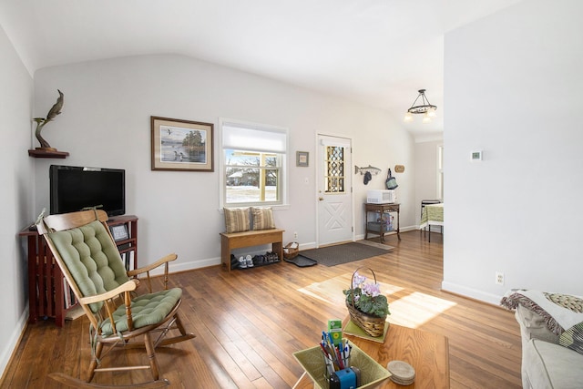 living room featuring vaulted ceiling, hardwood / wood-style flooring, and baseboards