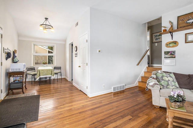 living room featuring visible vents, lofted ceiling, stairway, wood-type flooring, and baseboards