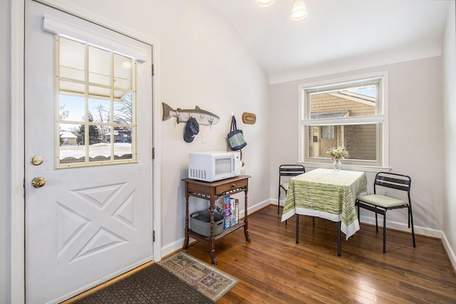 interior space featuring lofted ceiling, hardwood / wood-style flooring, and baseboards