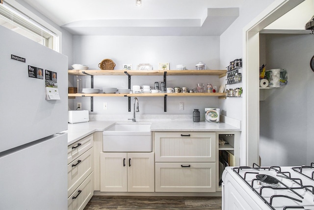 kitchen with a sink, open shelves, white appliances, and dark wood finished floors