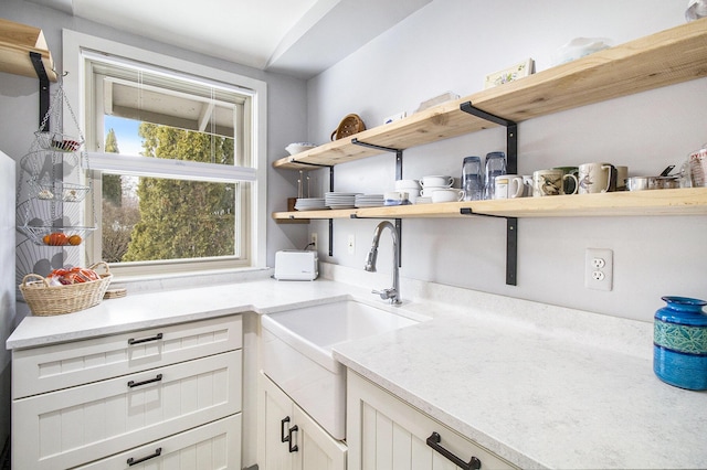 interior space featuring a sink, white cabinetry, and open shelves