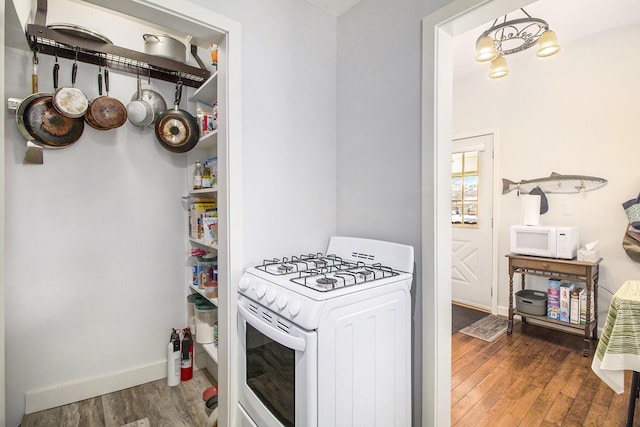 kitchen with white appliances, wood finished floors, and baseboards