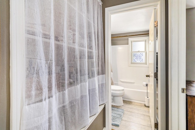 full bathroom with toilet, shower / tub combo with curtain, and wood finished floors