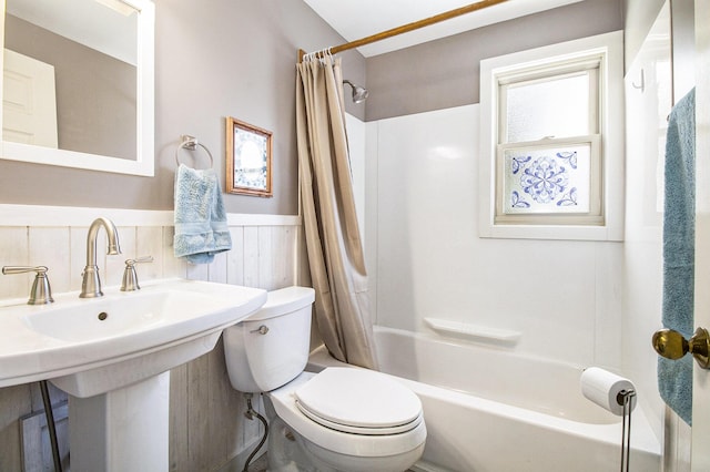 full bathroom with wainscoting, toilet, shower / tub combo with curtain, and a sink