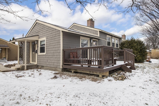 snow covered back of property featuring a deck and a chimney