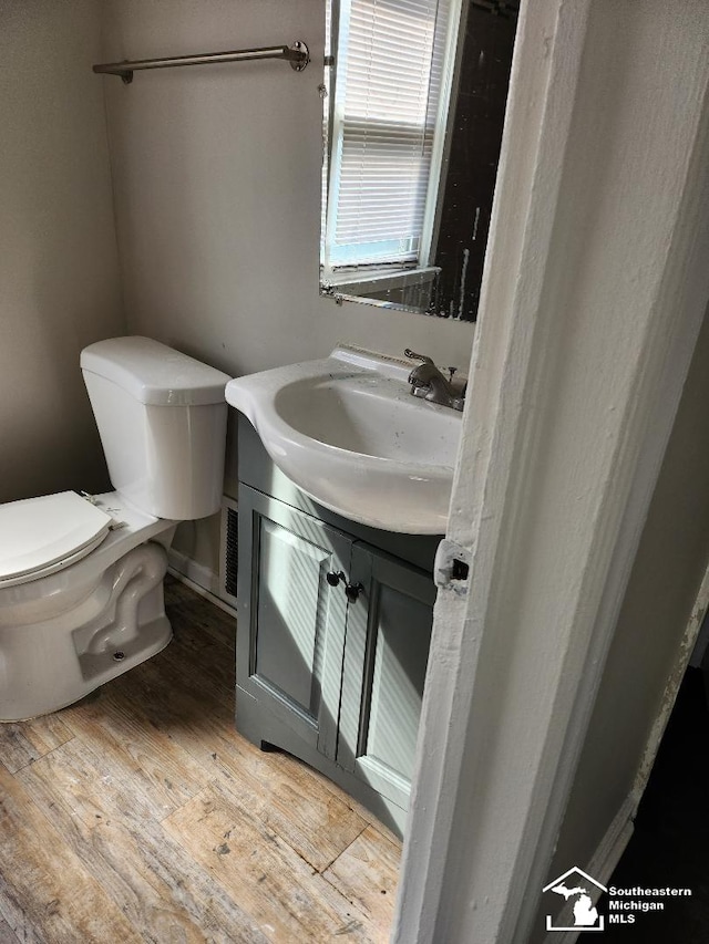 half bath with toilet, vanity, and hardwood / wood-style flooring
