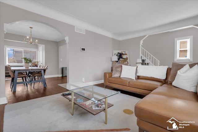 living room with visible vents, ornamental molding, wood finished floors, arched walkways, and a notable chandelier