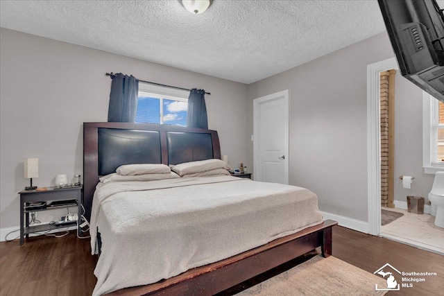 bedroom featuring wood finished floors, baseboards, and a textured ceiling