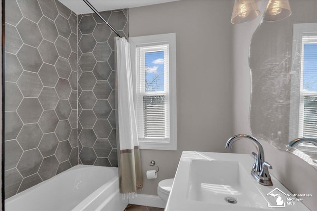 full bathroom featuring toilet, baseboards, a wealth of natural light, and a sink