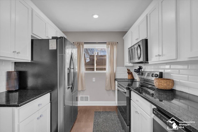 kitchen with visible vents, backsplash, dark wood-type flooring, stainless steel appliances, and white cabinetry