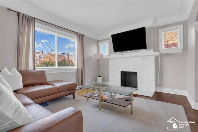 living area featuring a brick fireplace, wood finished floors, and baseboards