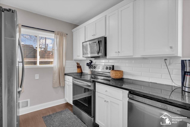 kitchen featuring appliances with stainless steel finishes, white cabinets, decorative backsplash, baseboards, and dark wood-style flooring