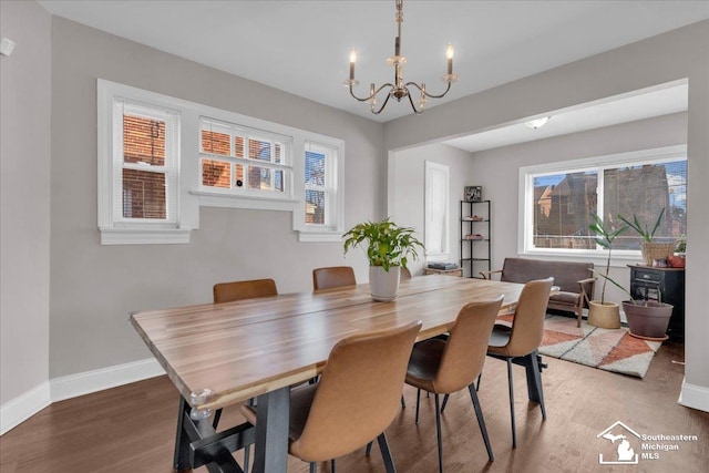 dining space with wood finished floors, baseboards, plenty of natural light, and a chandelier