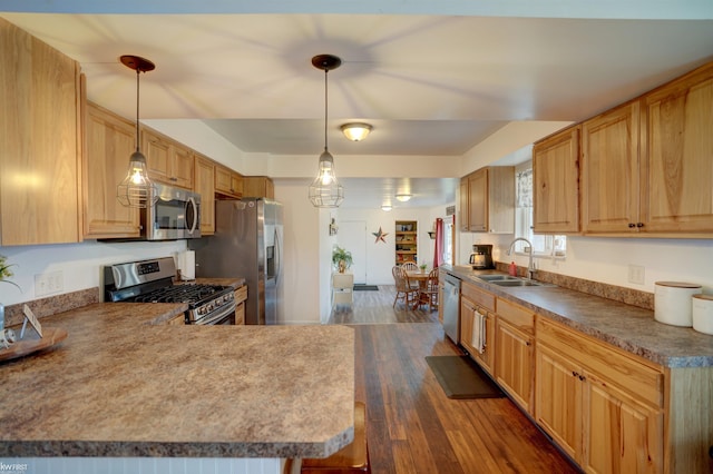 kitchen with dark wood-style floors, decorative light fixtures, appliances with stainless steel finishes, and a sink