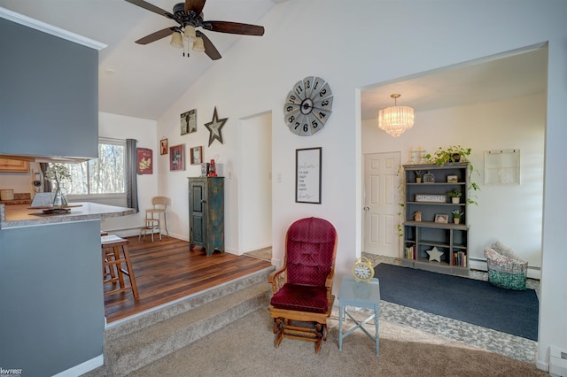 sitting room with a baseboard heating unit, ceiling fan with notable chandelier, baseboards, and high vaulted ceiling