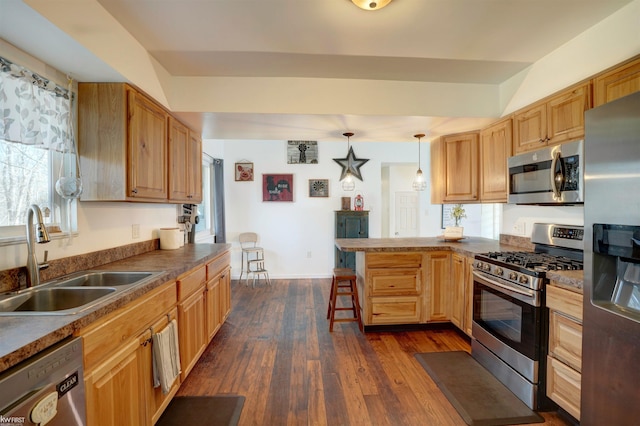 kitchen featuring dark wood-style floors, a breakfast bar, a peninsula, a sink, and stainless steel appliances