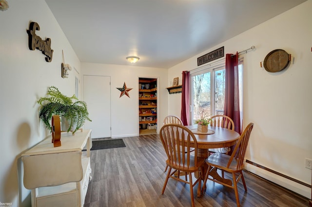 dining room featuring a baseboard heating unit, dark wood-style floors, and baseboards