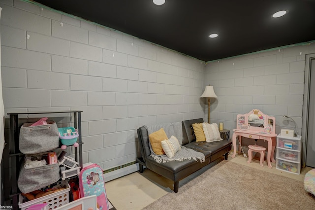 living area with baseboard heating, recessed lighting, and concrete block wall