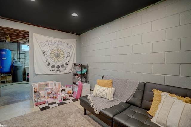 living area with recessed lighting, concrete block wall, and concrete floors