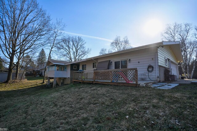 back of house with a deck, a lawn, and a garage