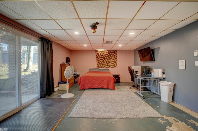 bedroom with access to exterior, a drop ceiling, concrete flooring, recessed lighting, and concrete block wall