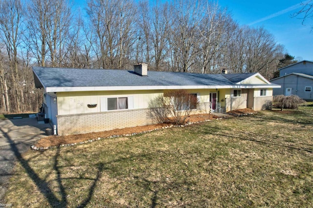 view of front of house featuring board and batten siding, a front lawn, brick siding, and a chimney