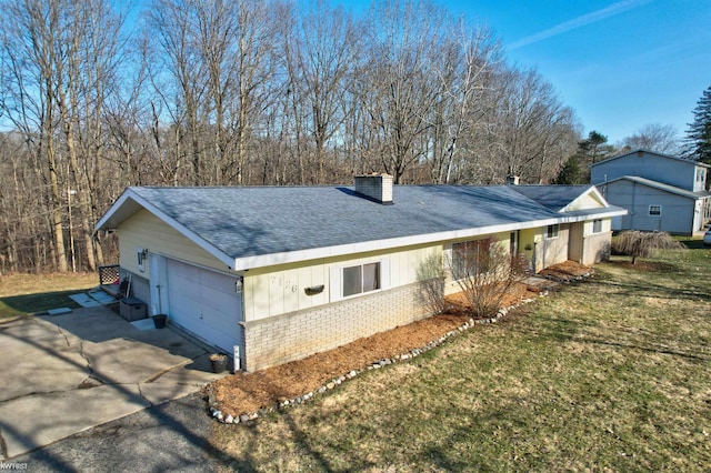 view of front of home with brick siding, a front lawn, a chimney, a garage, and driveway