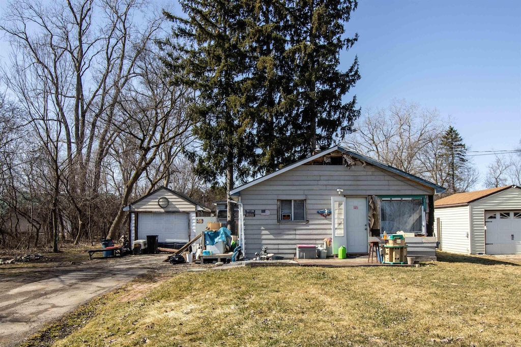 view of front of home featuring an outdoor structure, concrete driveway, a front lawn, and a detached garage