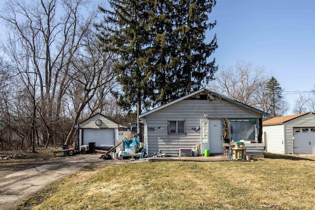 view of front of home featuring an outdoor structure, concrete driveway, a front lawn, and a detached garage