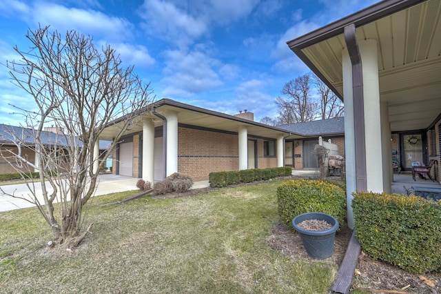 view of home's exterior with a chimney, concrete driveway, a garage, a lawn, and brick siding