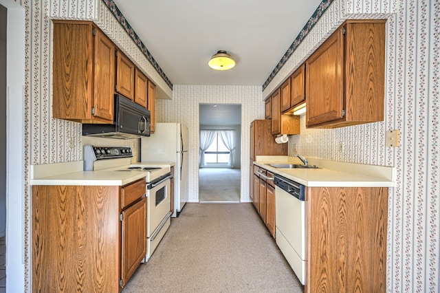 kitchen with white appliances, wallpapered walls, light countertops, and a sink