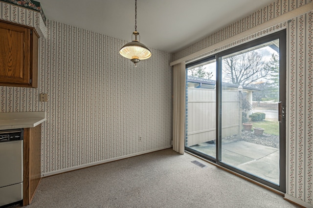 unfurnished dining area with wallpapered walls, carpet, visible vents, and baseboards