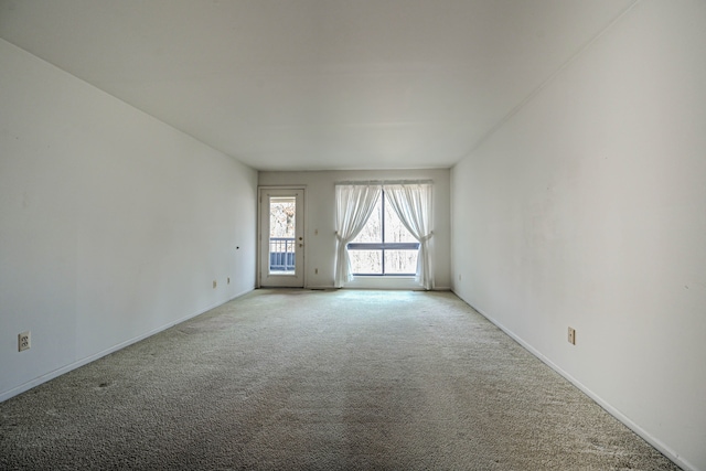 unfurnished room featuring light carpet and baseboards