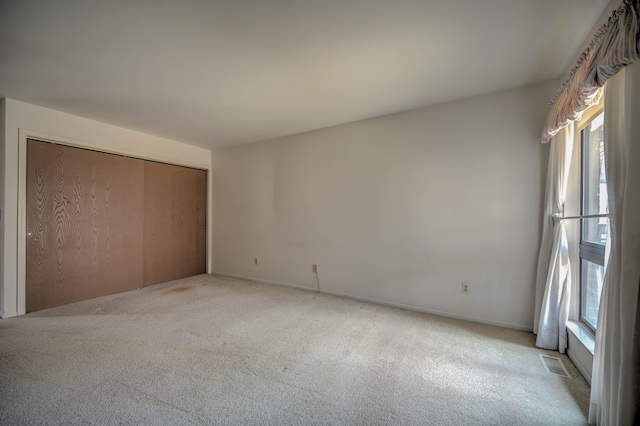 unfurnished bedroom featuring a closet, visible vents, light colored carpet, and baseboards