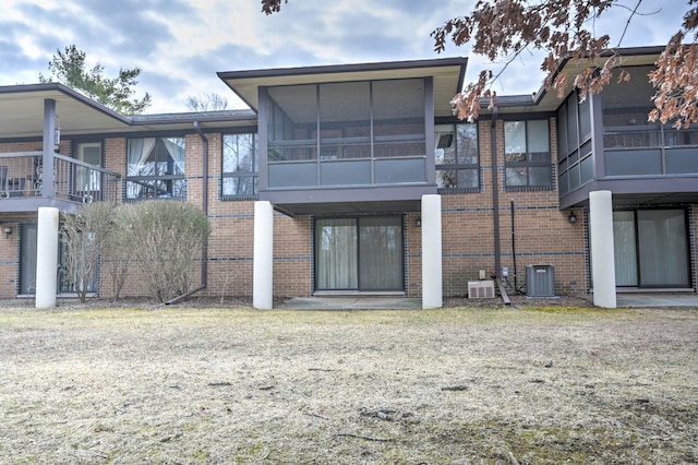 back of house featuring central air condition unit and brick siding