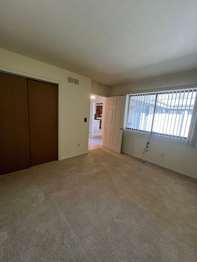 unfurnished bedroom featuring a closet, visible vents, baseboards, and carpet