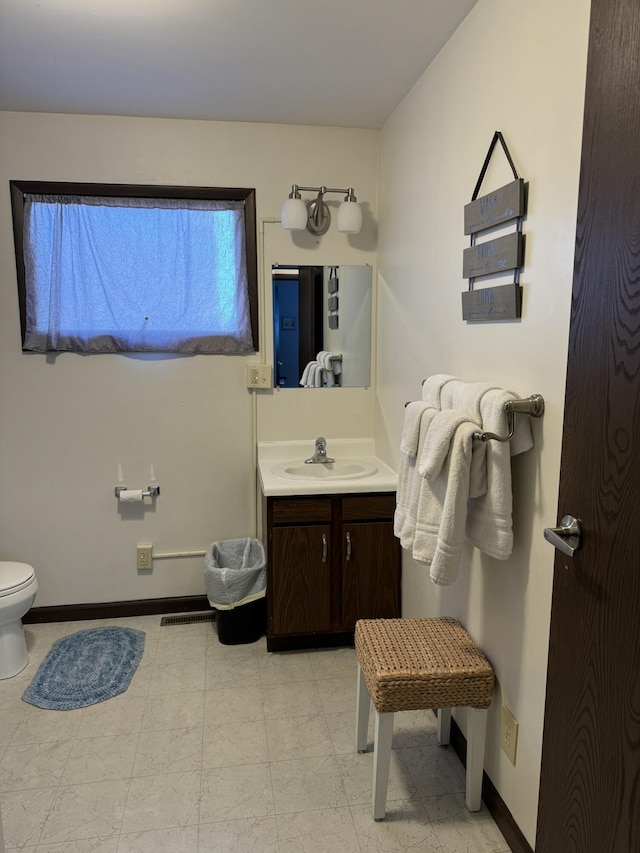 bathroom with baseboards, toilet, and vanity