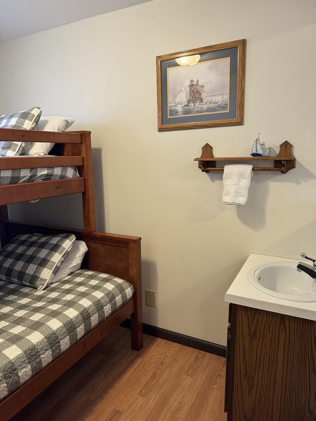 bedroom featuring a sink, baseboards, and light wood finished floors