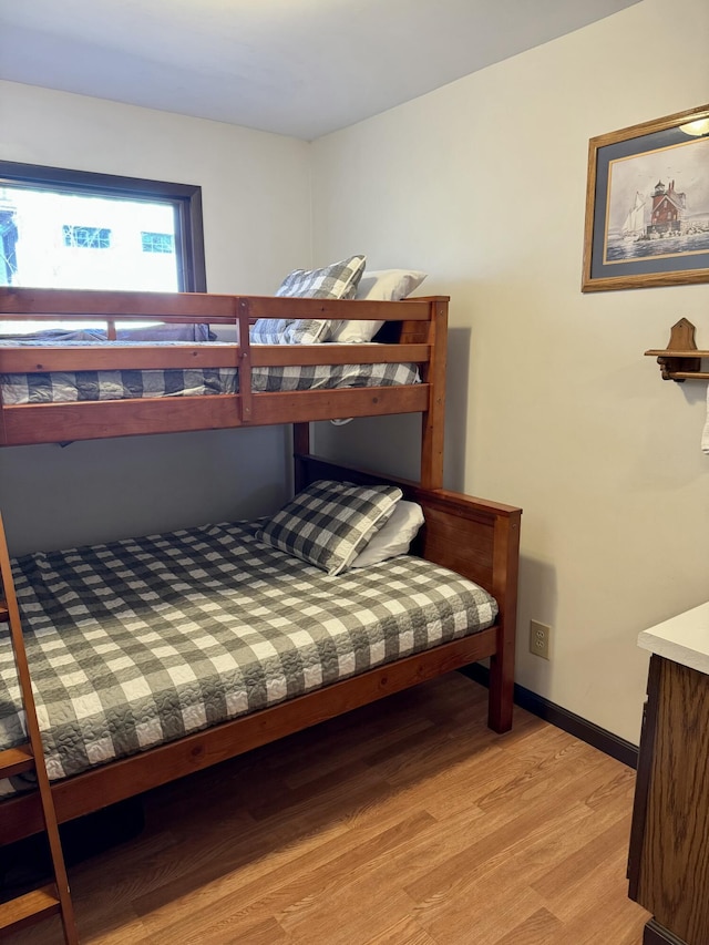 bedroom featuring light wood finished floors and baseboards